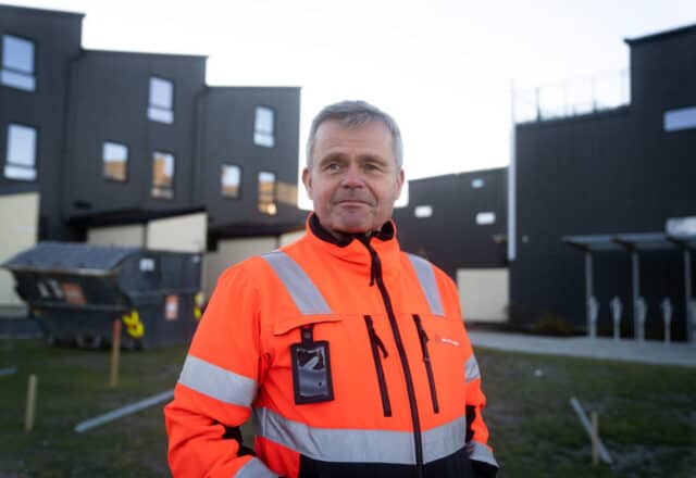 Arnstein Sørgård er byggvask-kunde. Her står han i verneklær med et nybygg i bakgrunnen.
