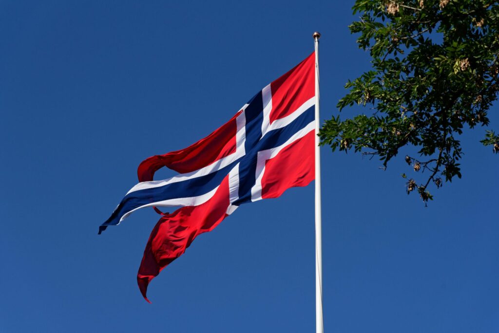 Norsk flagg i toppen av flaggstangen. Flagget vaier i vinden.