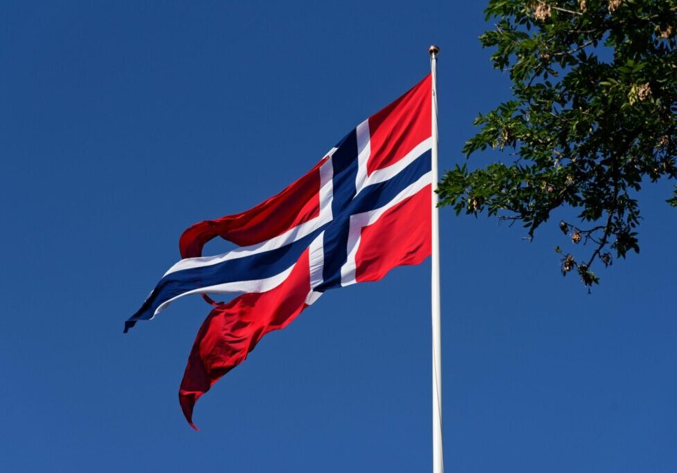 norskflagg Norsk flagg i toppen av flaggstangen. Flagget vaier i vinden.